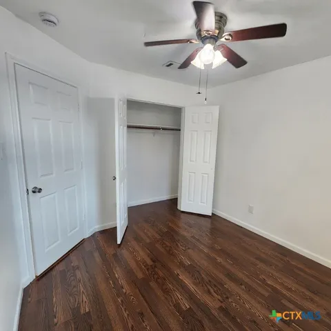 en empty room with wooden floor and fan