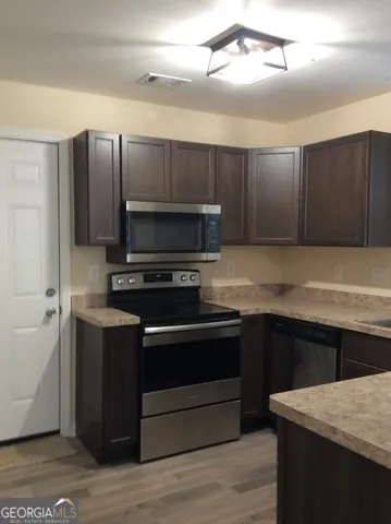 a kitchen with kitchen island granite countertop a sink cabinets and stainless steel appliances