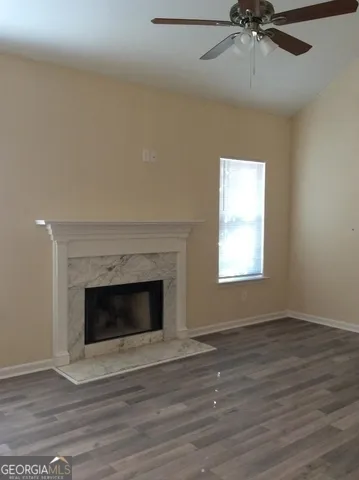 a view of an empty room with wooden floor and a fireplace