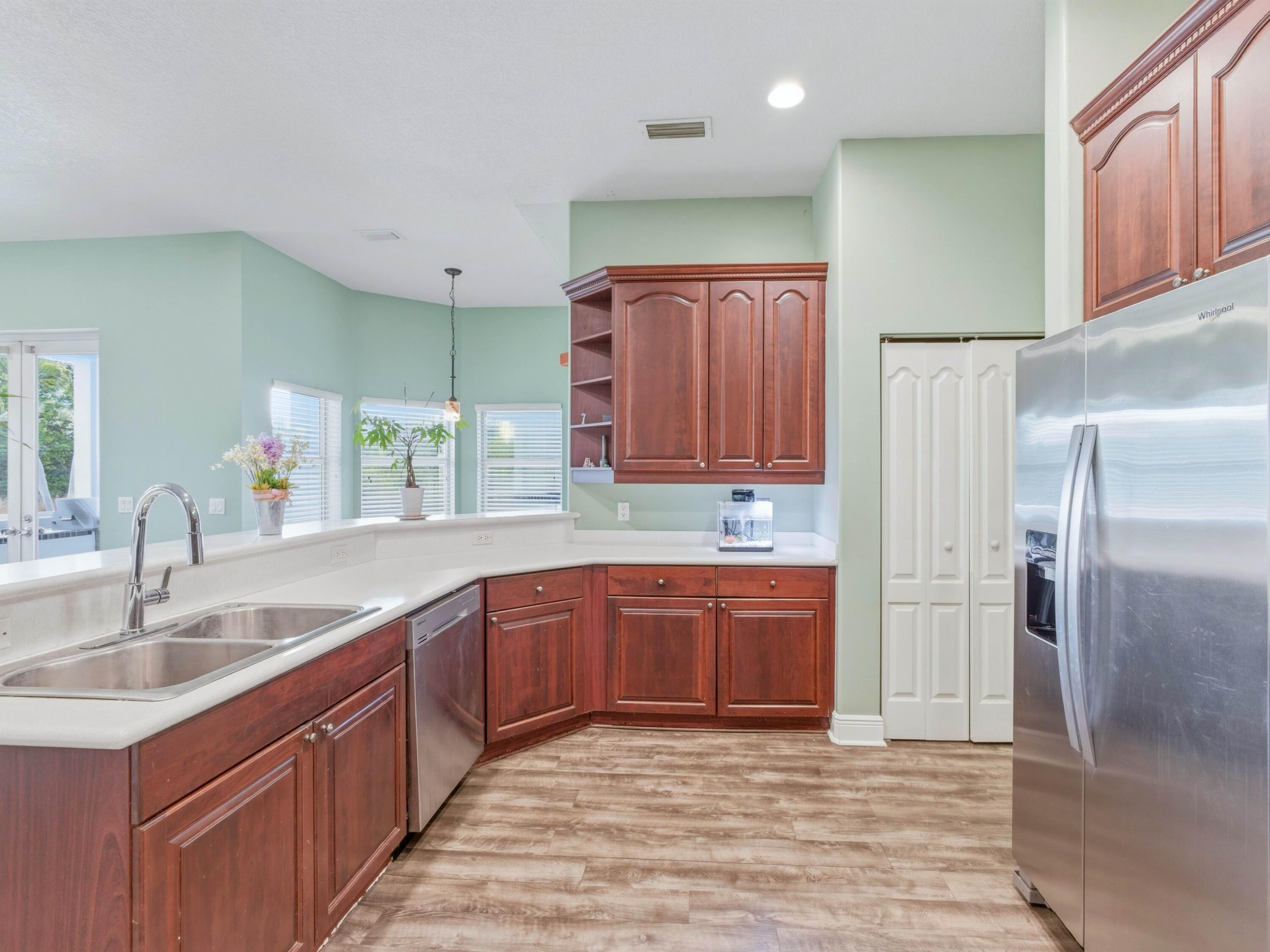 18852 43rd Road North The Acreage, FL 33470 - Photo 6 of 24 a kitchen with stainless steel appliances granite countertop a sink and dishwasher a refrigerator with wooden cabinets