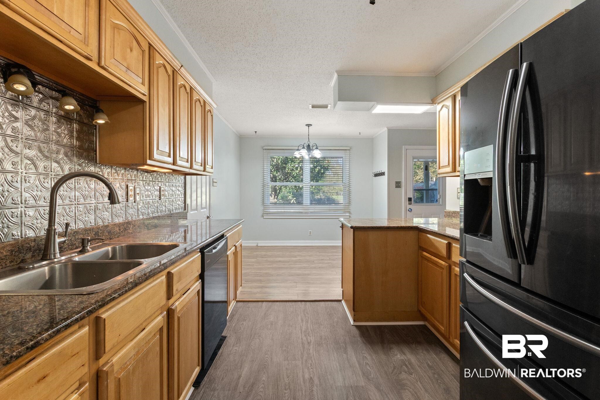 3864 Leroy Stevens Road Mobile, AL 36619 - Photo 11 of 33 Kitchen featuring black appliances, dark stone countertops, ornamental molding, dark wood-style floors, and backsplash