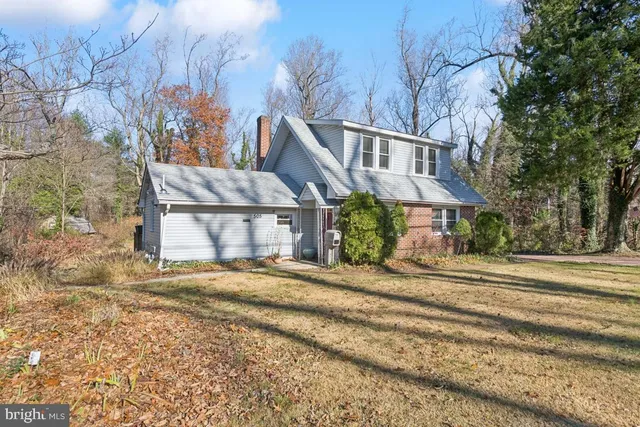a view of a house with a yard and large trees