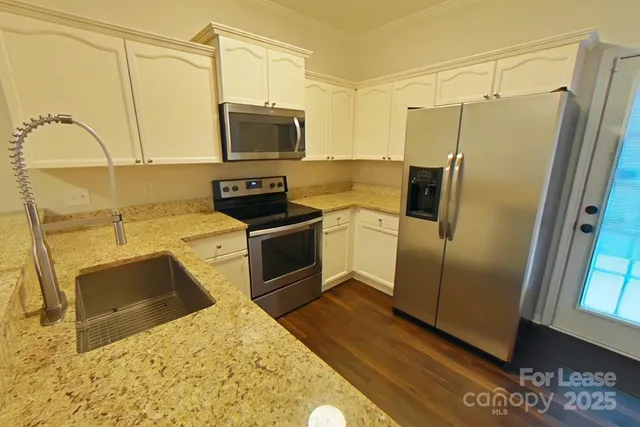 a kitchen with granite countertop a refrigerator and a sink