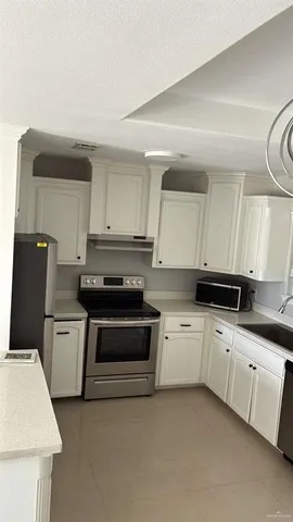 a kitchen with granite countertop a sink a stove a refrigerator and cabinets