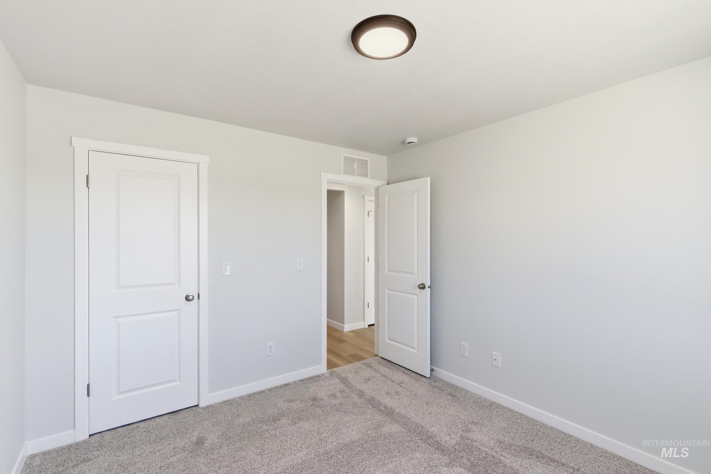 13677 Redway Court Caldwell, ID 83607 - Photo 27 of 35 Neutral wall color, two-panel interior doors, contemporary flush mount ceiling light fixture, baseboard trim, and light gray carpet