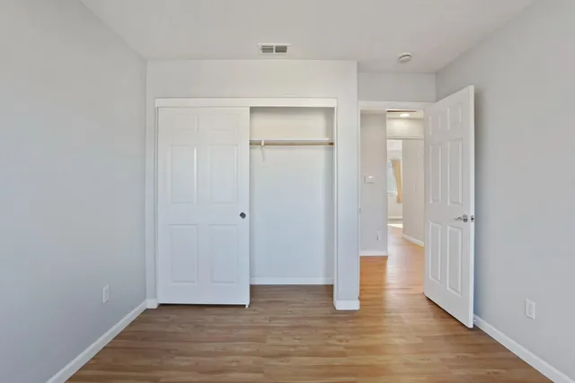 a view of an empty room with wooden floor and closet