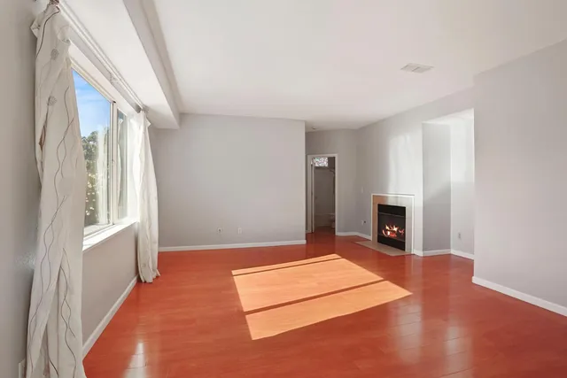 a view of an empty room with a fireplace and a window