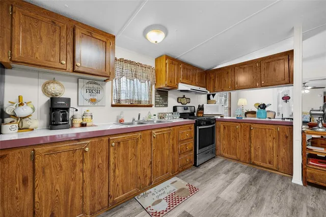 a kitchen with stainless steel appliances granite countertop a sink dishwasher stove and cabinets with wooden floor