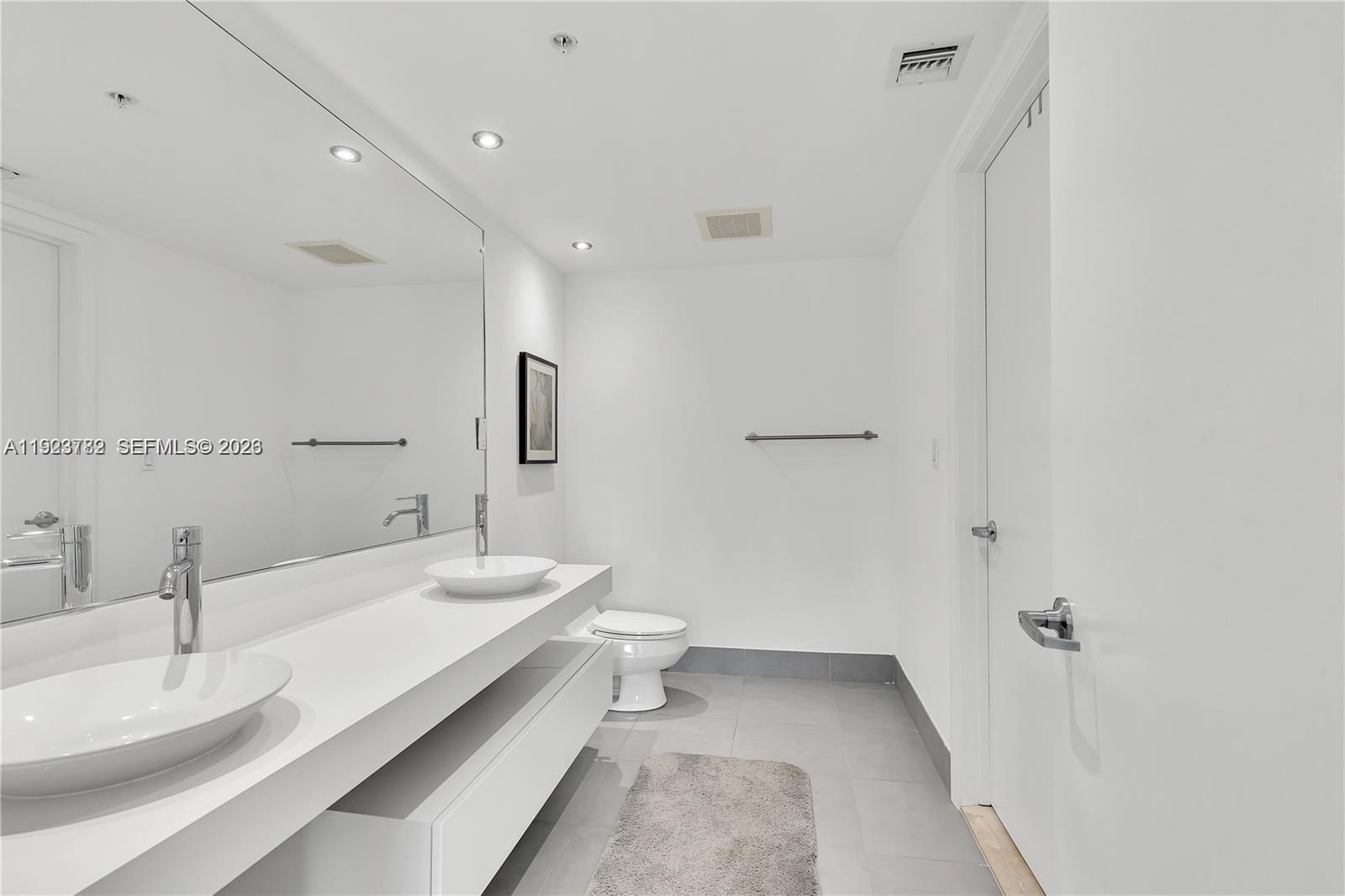 92 Southwest 3rd Street, Unit 3602 Miami, FL 33130 - Photo 6 of 11 a bathroom with a double vanity sink toilet and mirror