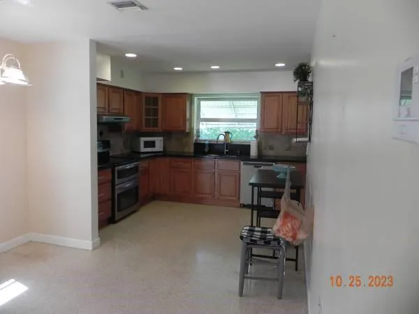 a kitchen with stainless steel appliances kitchen island granite countertop a stove top oven a sink and a refrigerator