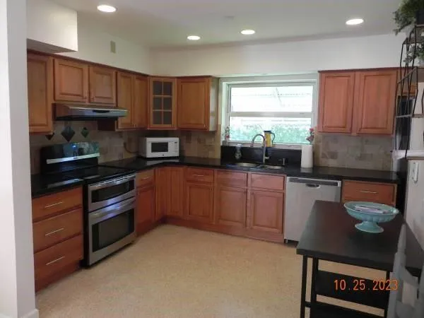 a kitchen with stainless steel appliances granite countertop a stove a sink and a microwave