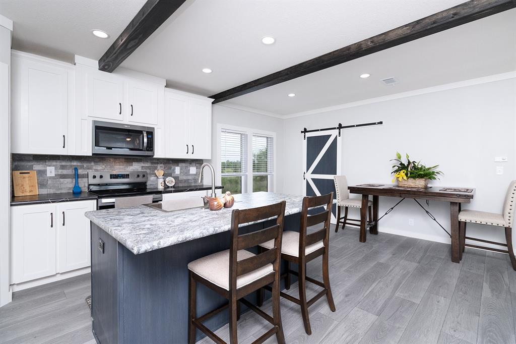 a kitchen with stainless steel appliances granite countertop a table chairs and a refrigerator