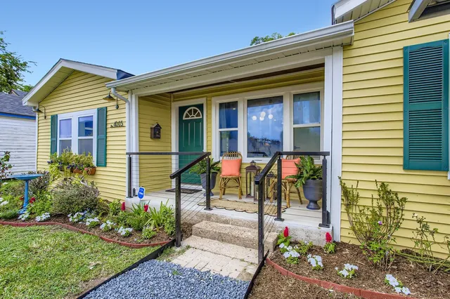 a view of a house with potted plants and a bench