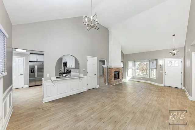 an empty room with wooden floor fireplace and windows