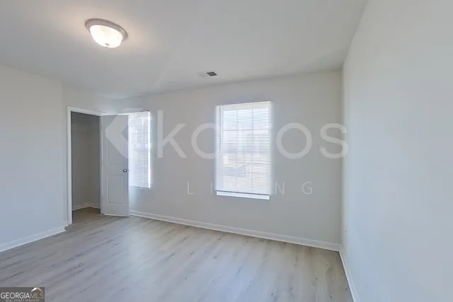 an empty room with wooden floor and windows