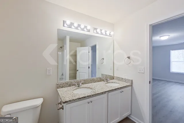 a bathroom with a granite countertop sink a toilet and a mirror