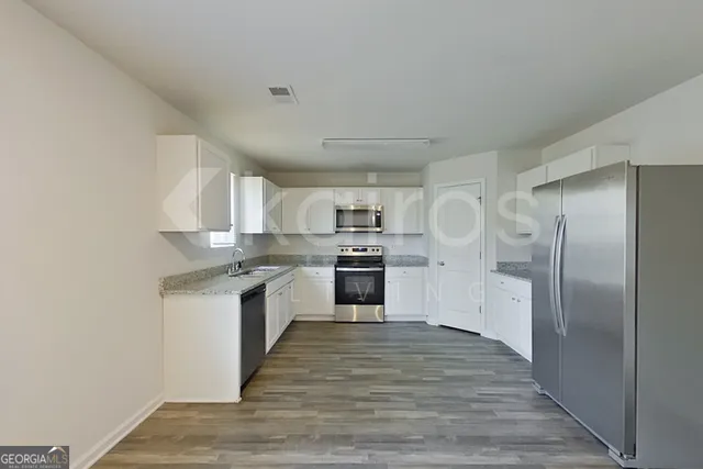a large kitchen with cabinets wooden floor and stainless steel appliances