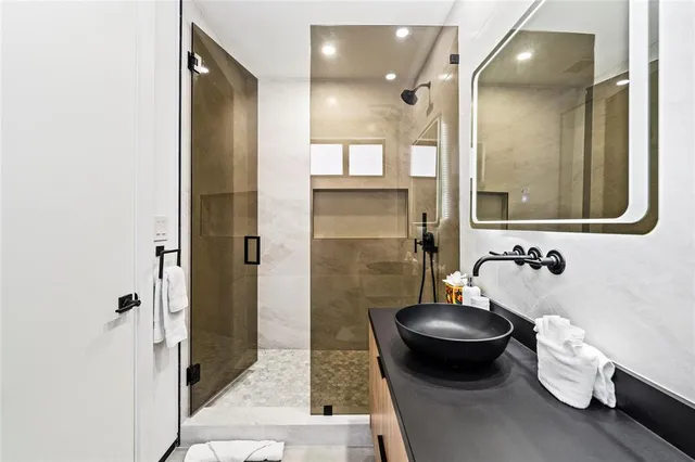 a bathroom with a granite countertop sink a mirror and a shower