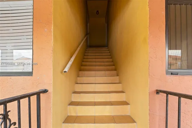 a view of staircase with lots of frames on wall and a window