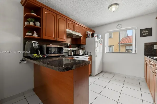 a kitchen with stainless steel appliances granite countertop a refrigerator a stove top oven a sink and dishwasher