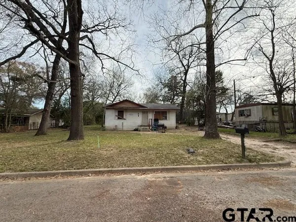 a view of a house with a yard covered in the forest