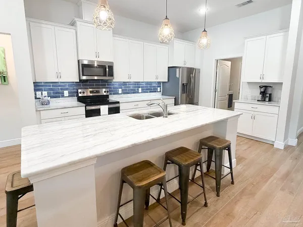 a kitchen with stainless steel appliances kitchen island granite countertop a table chairs microwave and sink