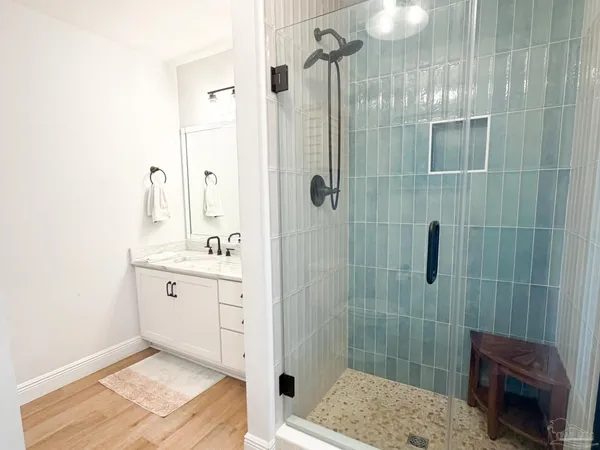 a bathroom with a granite countertop sink a mirror and shower