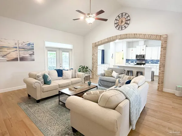 a living room with furniture a large window and wooden floor
