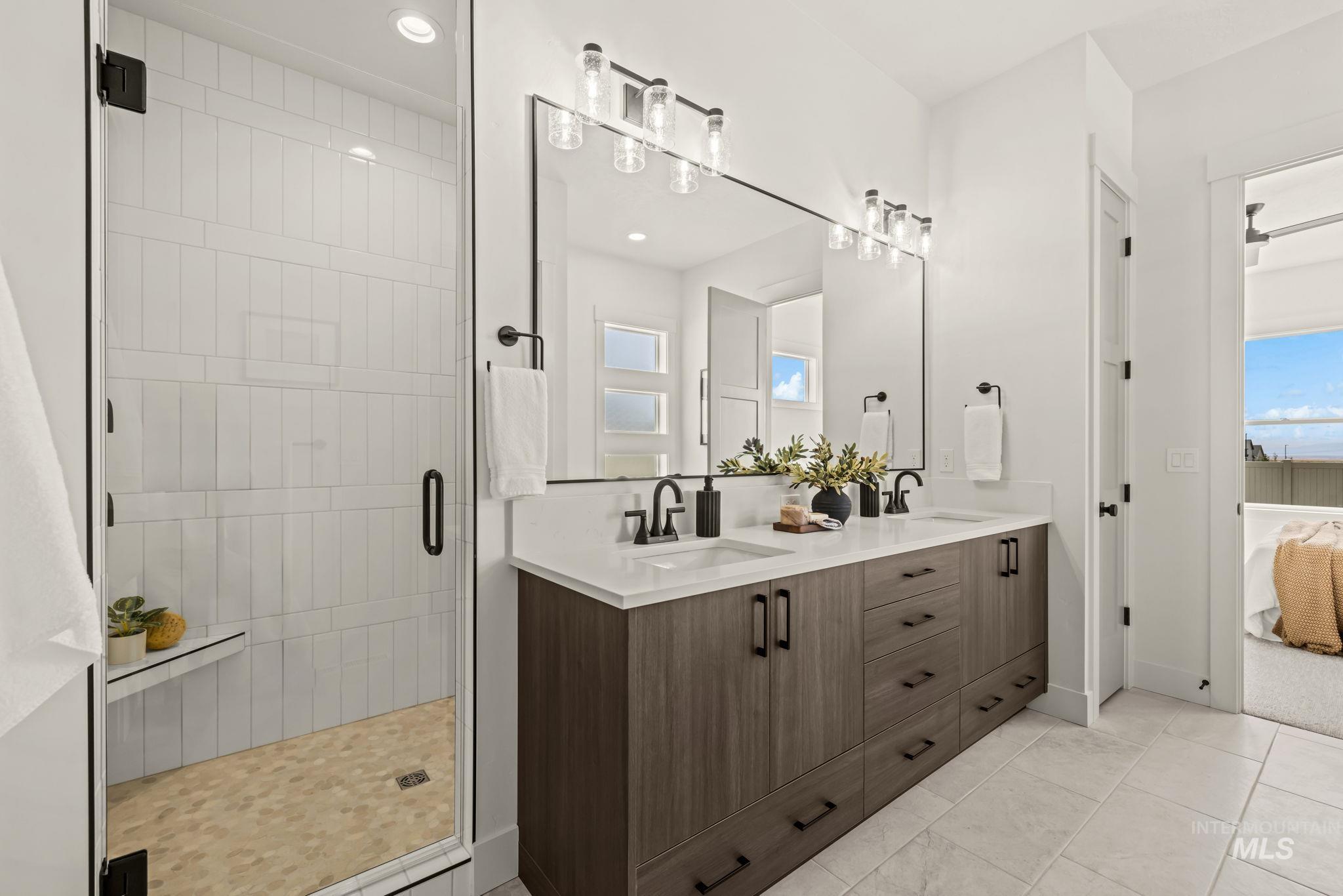 345 South Strut Way Boise, ID 83716 - Photo 31 of 50 Glass-enclosed shower with a built-in bench, dual vanity with a light-toned countertop, dark wood-finish cabinetry, and matte black hardware