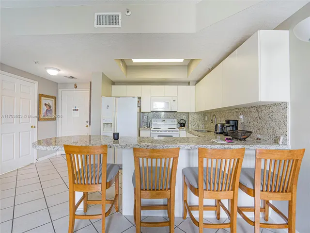 a kitchen with stainless steel appliances granite countertop a dining table chairs and white cabinets