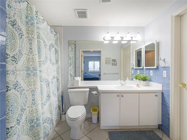 a bathroom with a granite countertop toilet a sink and a mirror