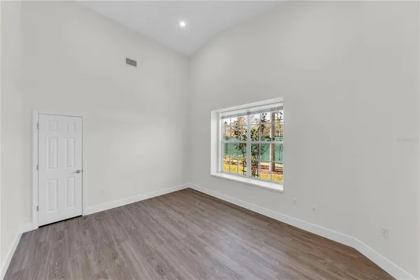 an empty room with wooden floor and windows