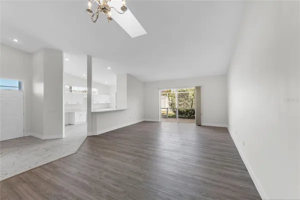 an empty room with wooden floor cabinet and windows