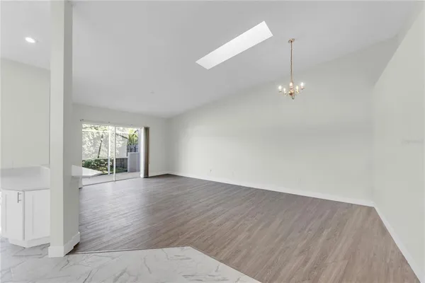 an empty room with wooden floor fan and window