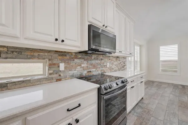 a kitchen with stainless steel appliances granite countertop white cabinets a microwave a sink and a counter space