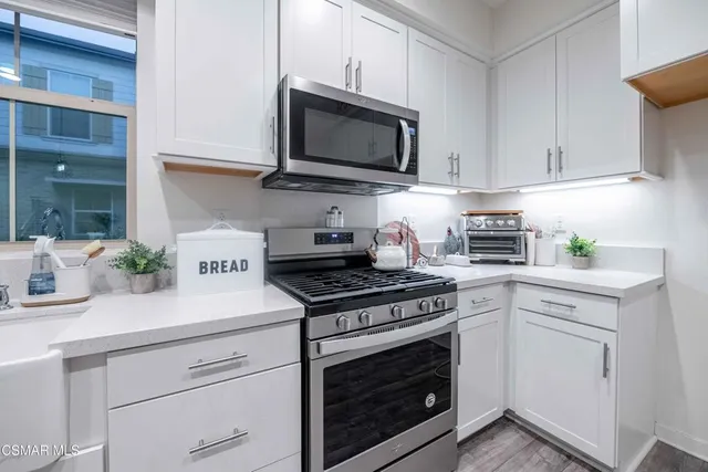a kitchen with a sink a center island stainless steel appliances and cabinets