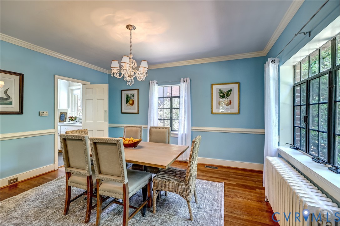4814 Riverside Drive Richmond, VA 23225 - Photo 14 of 39 a dining room with wooden floor a chandelier a wooden table and chairs