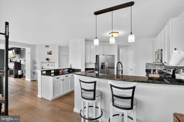 a kitchen with stainless steel appliances a stove a sink and white cabinets with wooden floor