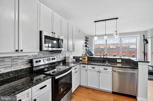 a kitchen with granite countertop a sink a stove and cabinets