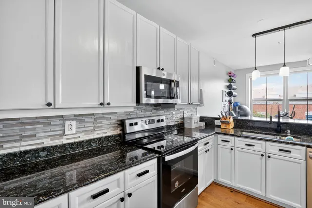 a kitchen with stainless steel appliances granite countertop a sink a stove and a microwave