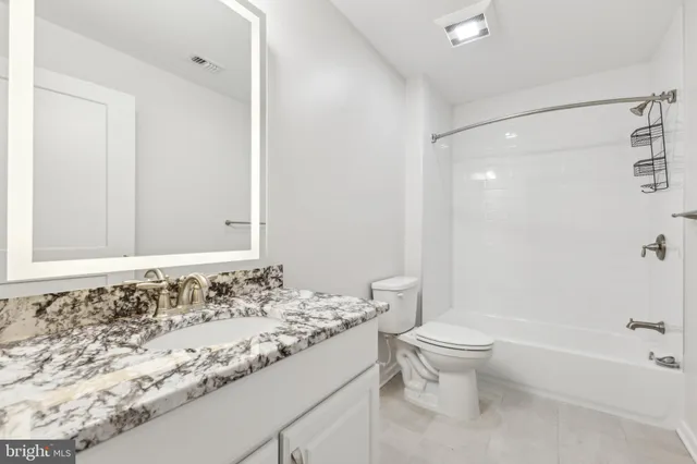a bathroom with a granite countertop sink toilet and shower