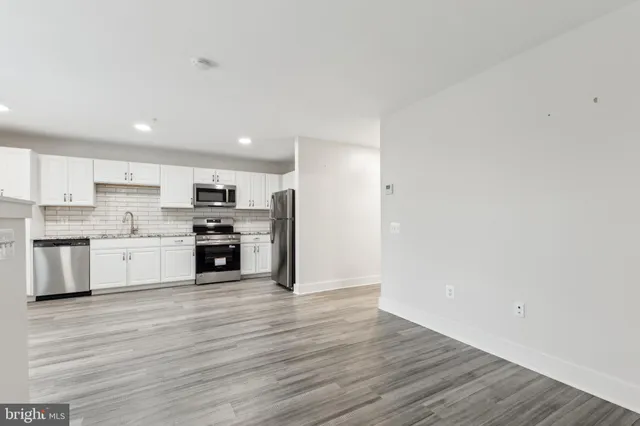 a kitchen with wooden floors stainless steel appliances and white cabinets