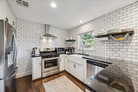 a kitchen with stainless steel appliances kitchen island granite countertop a dining table chairs and granite counter tops