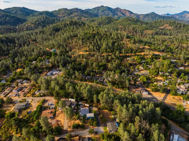 an aerial view of residential house with parking and trees