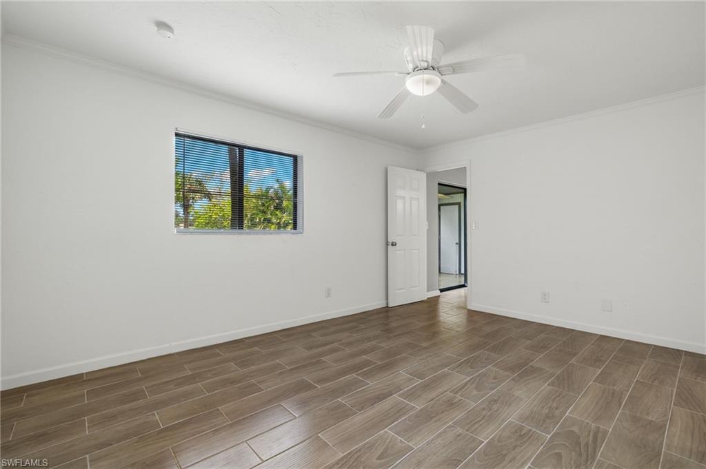 16540 Partridge Club Road, Unit 103 Fort Myers, FL 33908 - Photo 16 of 36 an empty room with wooden floor ceiling fan and windows