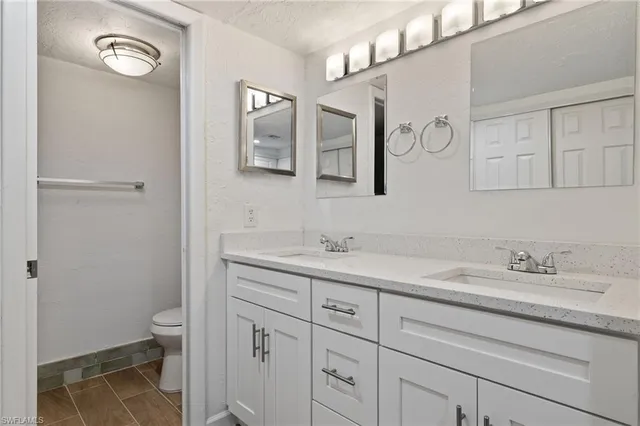 a bathroom with a granite countertop sink a toilet and a mirror