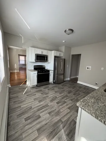 a living room with stainless steel appliances kitchen island granite countertop a stove and a refrigerator