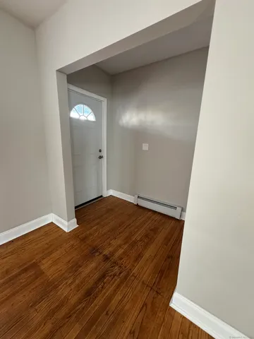 an empty room with wooden floor and entrance