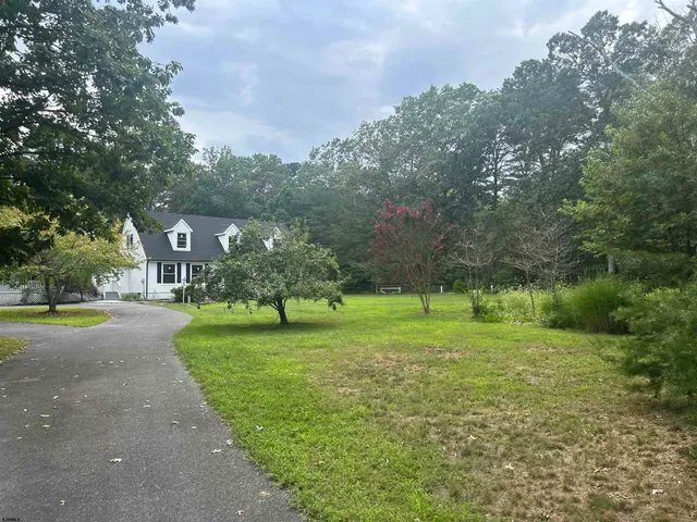 a front view of a house with a big yard and large trees