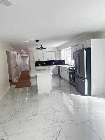 a kitchen with a refrigerator and a view of living room